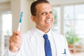 Middle age dentist man holding toothbrush and smiling Royalty Free Stock Photo