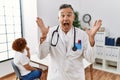 Middle age doctor man at the clinic with a patient celebrating crazy and amazed for success with arms raised and open eyes Royalty Free Stock Photo