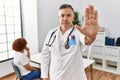 Middle age doctor man at the clinic with a patient doing stop sing with palm of the hand Royalty Free Stock Photo