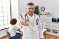 Middle age doctor man at the clinic with a patient smiling friendly offering handshake as greeting and welcoming Royalty Free Stock Photo