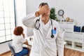 Middle age doctor man at the clinic with a patient smiling and laughing with hand on face covering eyes for surprise