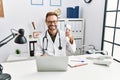 Middle age doctor man holding thermometer at the clinic looking positive and happy standing and smiling with a confident smile Royalty Free Stock Photo