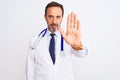 Middle age doctor man wearing coat and stethoscope standing over isolated white background doing stop sing with palm of the hand Royalty Free Stock Photo