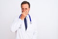 Middle age doctor man wearing coat and stethoscope standing over isolated white background smelling something stinky and