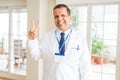 Middle age doctor man wearing medical coat and id card badge over white background smiling with happy face winking at the camera Royalty Free Stock Photo