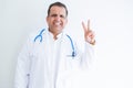 Middle age doctor man wearing stethoscope and medical coat over white background smiling with happy face winking at the camera Royalty Free Stock Photo