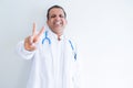 Middle age doctor man wearing stethoscope and medical coat over white background smiling looking to the camera showing fingers Royalty Free Stock Photo