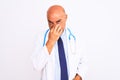 Middle age doctor man wearing stethoscope and tie standing over isolated white background smelling something stinky and