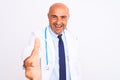 Middle age doctor man wearing stethoscope and tie standing over isolated white background smiling friendly offering handshake as Royalty Free Stock Photo