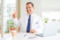 Middle age doctor man wearing white medical coat working with laptop at the clinic smiling with happy face winking at the camera Royalty Free Stock Photo