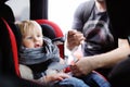 Middle age father helps his toddler son to fasten belt on car seat Royalty Free Stock Photo