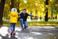 Middle age father showing his toddler son how to ride a scooter in a autumn park Royalty Free Stock Photo