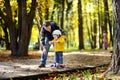 Middle age father showing his toddler son how to ride a scooter in a autumn park Royalty Free Stock Photo