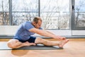 Man stretching hands to feet toes indoors