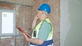 Middle age grey-haired man builder reading clipboard talking on smarpthone at construction site Royalty Free Stock Photo