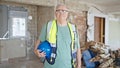 Middle age grey-haired man builder smiling confident holding hardhat at construction site Royalty Free Stock Photo