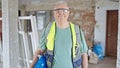 Middle age grey-haired man builder smiling confident holding hardhat at construction site Royalty Free Stock Photo