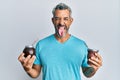 Middle age grey-haired man drinking mate infusion sticking tongue out happy with funny expression Royalty Free Stock Photo