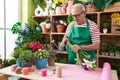 Middle age grey-haired man florist cutting stem at flower shop
