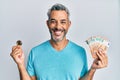 Middle age grey-haired man holding bunch of 50 euro banknotes and bitcoin smiling with a happy and cool smile on face