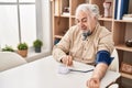 Middle age grey-haired man measuring pulse using tensiometer at home