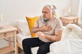 Middle age grey-haired man sitting on bed coughing at bedroom Royalty Free Stock Photo