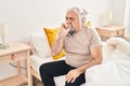 Middle age grey-haired man sitting on bed coughing at bedroom Royalty Free Stock Photo