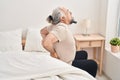 Middle age grey-haired man suffering for back injury sitting on bed at bedroom Royalty Free Stock Photo