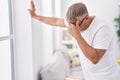 Middle age grey-haired man suffering dizzy standing at home