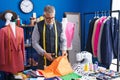 Middle age grey-haired man tailor cutting cloth at clothing factory