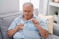 Middle age grey-haired man taking pill drinking glass of water at home Royalty Free Stock Photo