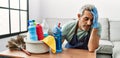 Middle age grey-haired man tired cleaning table at home