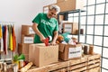 Middle age grey-haired man volunteer smiling confident packing books cardboard box at charity center Royalty Free Stock Photo