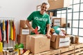 Middle age grey-haired man volunteer smiling confident packing books cardboard box at charity center Royalty Free Stock Photo