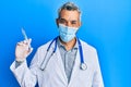 Middle age grey-haired man wearing doctor uniform and medical mask holding syringe looking positive and happy standing and smiling Royalty Free Stock Photo