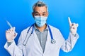 Middle age grey-haired man wearing doctor uniform and medical mask holding syringe smiling with an idea or question pointing Royalty Free Stock Photo