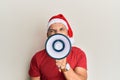 Middle age grey-haired man wearing santa claus hat screaming angry using megaphone over isolated white background Royalty Free Stock Photo