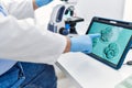 Middle age grey-haired man wearing scientist uniform looking embryology image touchpad at laboratory