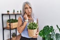 Middle age grey-haired woman holding green plant pot at home touching mouth with hand with painful expression because of toothache Royalty Free Stock Photo