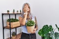 Middle age grey-haired woman holding green plant pot at home yawning tired covering half face, eye and mouth with hand Royalty Free Stock Photo