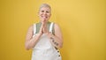 Middle age grey-haired woman smiling confident clapping applause over isolated yellow background