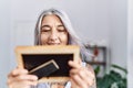 Middle age grey-haired woman smiling confident looking photo at home Royalty Free Stock Photo