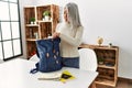 Middle age grey-haired woman smiling confident preparing trip backpack at home