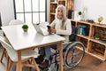 Middle age grey-haired woman using smartphone sitting on wheelchair at home Royalty Free Stock Photo