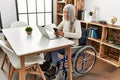 Middle age grey-haired woman using smartphone sitting on wheelchair at home Royalty Free Stock Photo