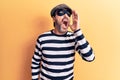 Middle age handsome burglar man wearing cap and mask over isolated yellow background shouting and screaming loud to side with hand Royalty Free Stock Photo