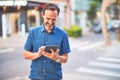 Middle age handsome businessman using tablet smiling on the street Royalty Free Stock Photo