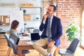 Middle age handsome businessman wearing glasses sitting on desk at the office with hand on chin thinking about question, pensive Royalty Free Stock Photo