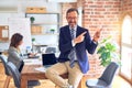 Middle age handsome businessman wearing glasses sitting on desk at the office smiling and looking at the camera pointing with two Royalty Free Stock Photo