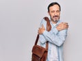 Middle age handsome businessman wearing leather bag over isolated white background hugging oneself happy and positive, smiling Royalty Free Stock Photo